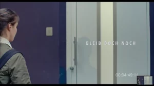 Szene aus dem Film „Bleib doch noch“: eine Frau steht vor einer geschlossenen Tür